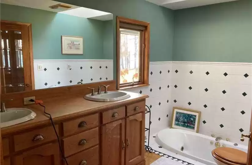 primary suite bathroom with taller double sink cabinet & sunken bathtub